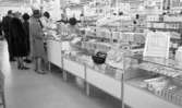 Väsktjuvar, Malmströms, Studenten 2, Väsktjuvar 20 april 1966

I en affär står tre damer i hatt samt en herre och handlar vid disken. Bakom disken vid kassaapparaten står två kassörskor och betjänar kunderna. Två handväskor ligger bland varorna som i det här fallet råkar vara tandkrämstuber. Den ena handväskan är öppnad.