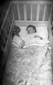 Byggspecial Oxhagen 11 februari 1966

En liten baby ligger i en spjälsäng i området Oxhagen i Örebro. I sängen finns lakan, täcke och kudde samt en nalle i ena hörnet. Babyn är klädd i en liten vit dress.