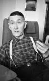 Diabetiker, 5 februari 1966

En äldre man i rutig skjorta, hängslen och byxor sitter i en fåtölj. Han håller upp sin vänstra hand i en gest. I bakgrunden hänger en tavla.