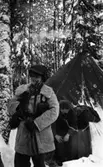Rycket in i lumpen 8 februari 1966

Två soldater under en militärövning. Soldaten i förgrunden har en vit överrock ovanpå sin militäruniform samt ett gevär i sin högra hand. Soldaten i bakgrundenär i färd med att kliva ut ur ett militärtält. Det har snöat mycket.