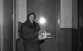 Tidningsbud 12 februari 1966

Ett tidningsbud, en kvinna, klädd i kappa och mössa står i trapphuset med en bunt tidningar i famnen utanför en lägenhet och har precis placerat en tidning i brevinkastet.