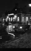 Vårregn, 31 januari 1966

Utanför Centralstationen i Örebro en regnig vinterkväll. Tre bilar står parkerade utanför byggnaden och två personer syns i bakgrunden. Det ligger snö på marken.