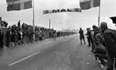 Cykel, 6 juni 1966

Ett antal cyklister cyklar in i mål under en tävling. Publik står på båda sidor om vägen och tittar på. Två svenska flaggor står uppställda vid var sin sida om vägen. Över vägen hänger en skylt med texten: 