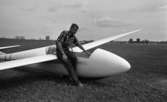 Beg. bilar, Ferieskola, Bodenkille slog rekord 14 juli 1966

En ung man klädd i rutig skjorta, långbyxor samt sandaler sitter på vingen till ett litet flygplan. Planet ligger på marken.