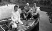 Missionärer i Kongo 29 augusti 1967

En äldre man klädd i ljus kostym, vit skjorta, mörk slips och som bär glasögon sitter i aktern på en båt på en sjö. Bredvid mannen sitter en äldre kvinna i en ärmlös, kort klänning. Också hon bär glasögon. I fören sitter en pojke i vit tröja, vita byxor och mörka skor. Han håller ett halvätet äpple i sina händer.