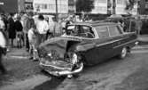 Krock Baronbacken 7 aug 1967

En mörk bil som varit med om en krock och har intryckt motorhuv står på gatan. Runtomkring står en massa människor. Byggnader syns i bakgrunden.