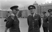 Kungen 13 28 augusti 1967

Kung Gustav VI Adolf besöker Örebro Livregementes Grenadjärer i Grenadjärsstaden. Ett antal män står uppställlda på regementsgården klädda i militäruniformer liksom kungen. Den sistnämnde står och samtalar med en general. Två andra militärer står till höger. Till vänster i bakgrunden syns en fotograf.