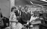Orubricerad 18 maj 1967

Fyra personer- två kvinnor och två män- poserar för kameran. Kvinnan till vänster sitter på en cykel klädd i en kort, ljus klänning med krage och håller en blombukett i höger hand. En man i mörk kostym står bredvid henne och håller om henne med sin högra arm. En till kostymklädd man står bredvid honom och bredvid denne man stpr en kvinna i vit kappa och håller en radio i sina händer med en bukett blommor ovanpå.