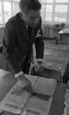 Kembels slutar, Blå stjärnan, 8 juli 1967

En man klädd i randig kostym, vit skjorta och mörk slips står och pekar på en bild i en tidning som ligger uppslagen på ett bord.