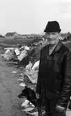 Klagomål på sophög vid flygfältet 10 maj 1967

En äldre herre klädd i svart skinnjacka, svarta byxor och svart hatt står med en hund på en soptipp nära flygfältet i Örebro. Ett bostadsområde ligger i bakgrunden.