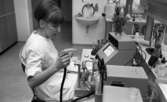 Lasarettet 14 juni 1967

En laboratorieassistent klädd i vit arbetsrock sitter vid sitt skrivbord inne i ett laboratorium på Örebro sjukhus och håller i laboratorieutrustning. Runt henne på bordet står provrör fyllda med substanser, mätapparater, nålar etc.