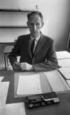 Gymnasielgh, Fick körkort, Domuschefer, Socialhögskolan 9 juni 1967

En man i ljus kostym, vit skjorta och svart slips sitter vid ett skrivord och håller en penna i sin högra hand.
