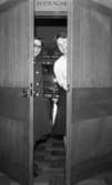 Lo- Handels 17 oktober 1966

Två kvinnor står i en dörröppning med dörren halvöppen och ler. Den ena bär mörk kavaj med vita knappar, mörk kjol, mörka skor samt glasögon. Den andra bär ljus blus, mörk kjol och mörka skor. Rummet bakom dörren skymtar i bakgrunden. Ovanför dörren syns texten 