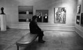 Länsmuseet slut..., 22 november 1966

En äldre dam klädd i svart kappa, svart basker, ljus halsduk, svarta byxor och svarta skor sitter på en soffa i Länsmuséet i Örebro. Hon betraktar tavlor som hänger på väggen. En skulptur syns även i bakgrunden till vänster.