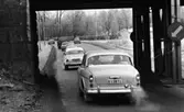 Länsläkaren, Trafiken 24 december 1966

Ett antal bilar och en lastbil kör på en gata. I förgrunden syns en tunnel. Byggnader syns i bakgrunden. Det ligger snö på marken.