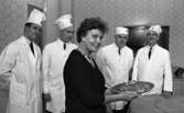 Minnesutställning se, Sockerbagare hos Thyra 7 april 1967

Fyra sockerbagare i vita arbetskläder med vita hattar till står inne i ett stort rum bredvid en äldre dam i svart dräkt och med vita pärlor runt halsen. Hon håller i ett silverfat med en tårta på.