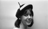 Modenummer 21 oktober 1966

Närbild på en ung kvinna som är modell. Hon har en vit- och brunschackrutig basker på huvudet. Hon bär vita pärlörhängen i öronen.