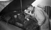Modevisning, Görtz motor (Rep av oil) 6 april 1967

En mekaniker arbetar i en verkstad med en bil. Han är i färd med något i motorhuven. Han är klädd i arbetsklädsel och mörk keps.