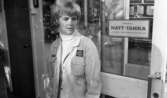 Bensinautomat 29 oktober 1966

Inne i en Shellmack står en kvinna ur personalen klädd i arbetskläder. På en skylt bakom henne står texten: 
