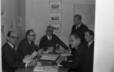 Lungkliniken, Nappivalen, Grekiskt handarbete 11 december 1967

Sex herrar varav fem är klädda i svarta kostymer, vita skjortor och ljusa slipsar är samlade kring ett skrivbord inne i ett rum. Tre av herrarna bär glasögon. Fem av herrarna sitter ned vid bordet och en står upp. Den sjätte mannen är klädd i mörk tröja, vit skjorta och slips och sitter i högsätet och håller i en ordförandeklubba.