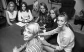 Miss Backfisch Kandiden, Travtipset, Möbler på golvet 7 oktober 1967

Sju fotomodeller sitter samlade runt ett bord i ett rum.