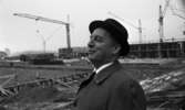 Oxhagen III 11 november 1967

Närbild på en byggmästare (troligtvis) under byggnadsuppförande i Oxhagen. Han är klädd i svart hatt, grå rock, vit skjorta och svart slips. Byggnadsarbetare syns på ställningar i bakgrunden. Lyftkranar syns även.