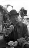 Wadköping 1 TV-inspelning 31 maj 1968

Den kände skådespelaren Edvin Adolphson fikar med kaffe och bulle under en paus i filminspelningen av Markurells i Wadköping av Hjalmar Bergman. Han är klädd i 1800-talskläder. I bakgrunden syns en annan manlig skådespelare samt filmkamera och en stor strålkastare.