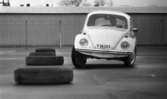 Wv Bilnytt 24 november 1967

En man testkör en vit folkvagn på en asfaltplan. Bildäck ligger utplacerade på marken och han kör bilen i sicksack mellan dem. En avlång byggnad syns i bakgrunden.
