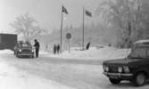 Ånnaboda 12 februari 1968

Bilar och människor befinner sig vid en parkering utanför en byggnad på vintern i Ånnaboda. Det ligger snö på marken. Två bilar står i kö efter varandra och vid den främre bilen står en äldre herre som troligtvis är en parkeringsvakt. Han har en liten biljettmaskin hängande med i rem på sin vänstersida på kroppen.