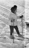 Ånnaboda 29 januari 1968

Närbild på en flicka i sexårsåldern som åker skidor i Ånnaboda. Hon är klädd i en vit jacka, svarta byxor, ljusa vantar och vita pjäxor. Hon har stavar i händerna och skidor på fötterna.