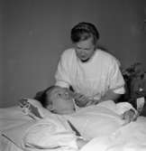 Poliosjuka får hjälp av anhöriga.
23 juli 1955.
