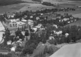 Flygfoto över Sköllersta, kyrkan och bostadshus.
Bilden tagen för vykort.