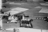 Flygfoto över Rinkaby kyrka, bostadshus och byggnader.