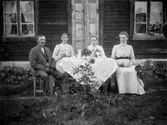 Fyra personer vid fikabordet, bostadshus.