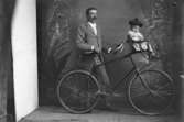 En man med cykel och en liten flicka i barnstol på cykeln.