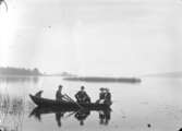 Sjöutsikt, fyra personer och en hund i en roddbåt.
