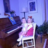 Rumsinteriör, två barn vid pianot.
Bertil Larsson
