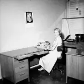 Kontorsinteriör, en kvinna vid skrivmaskinen.
Wigrell & Co.