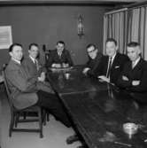 Rumsinteriör, grupp sex män vid bordet, styrelsen.