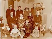 Rumsinteriör, familjegrupp 11 personer.
Fam. Andersson med blommor, högtid.