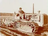 En man, en traktor av märket Caterpillar diesel.
(JUF) Örebrobygdens JUF-avd.