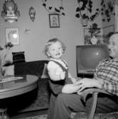 Rumsinteriör, en man och ett litet barn.Fru Britta Jönsson (beställare ?).