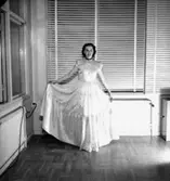 Interiör, en kvinna.
Konsums långa klänning.