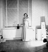 Interiör, en kvinna.
Konsums långa klänning.