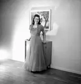 Interiör, en kvinna.
Konsums långa klänning.