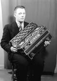 En man med musikinstrument (dragspel).
Olle Ljunggren eller Olle Fransson (?). (Se likheten med mannen på bild OLM-91-102-8291, Olle Fransson)
