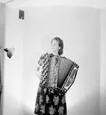 En kvinna med musikinstrument (dragspel).
Fröken Wettner