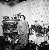 Rumsinteriör, en kvinna, högtid.
Stålberg-Larsson.