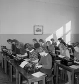 Klassrumsinteriör, flickgrupp, maskinskrivning.
P.M.