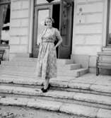 En kvinna. Bostadshus i bakgrunden.Bertil Sehlin (beställare).